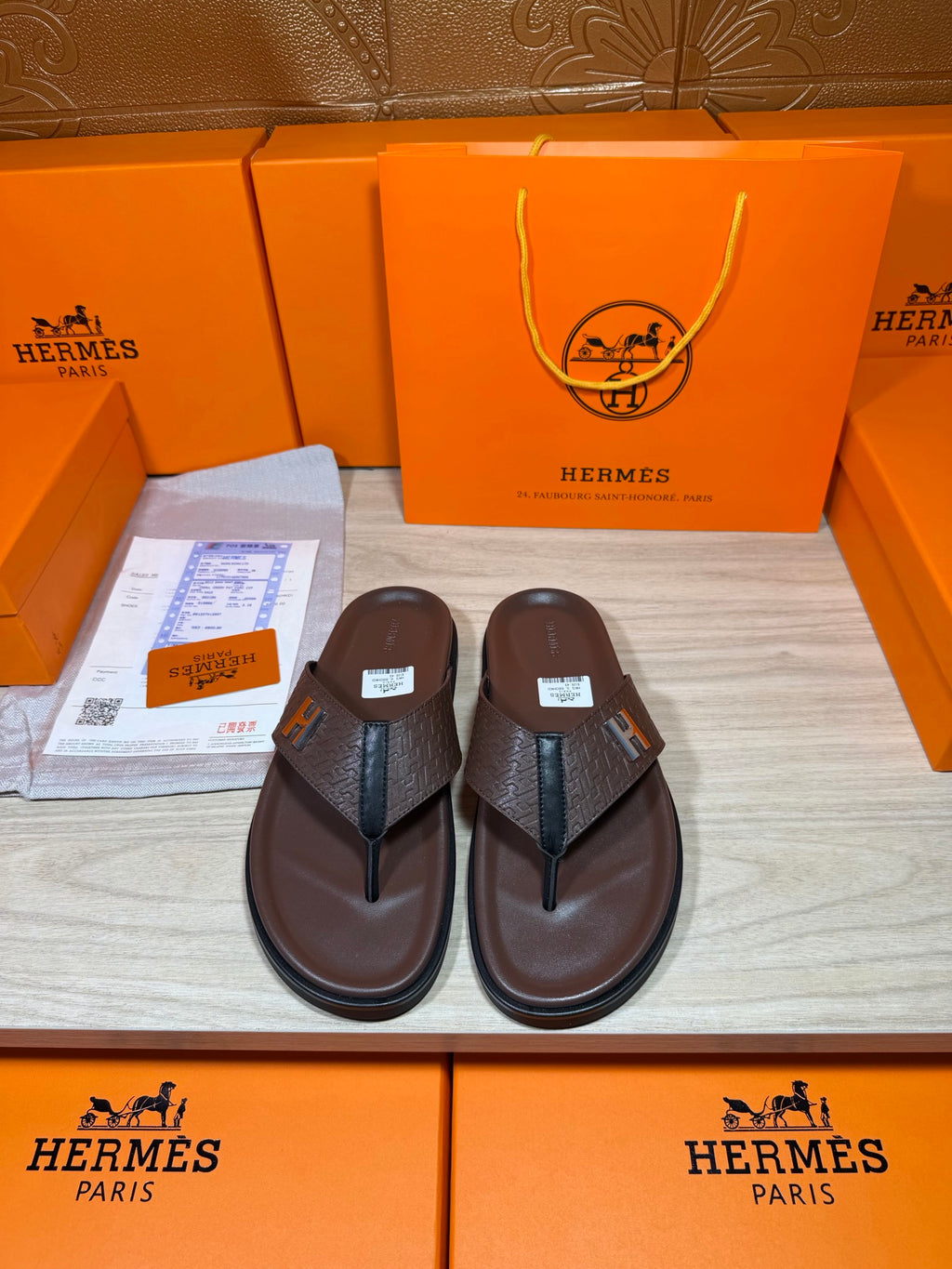 Brown leather flip-flop sandals with dark H strap detail on upper