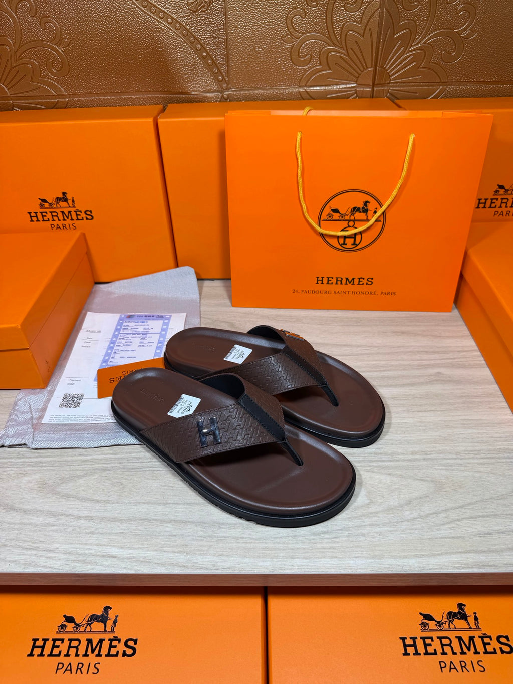 Brown leather flip-flop sandals with H strap detail, angled view