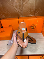 Hermes thong sandal held up, brown footbed with blue strap and H logo