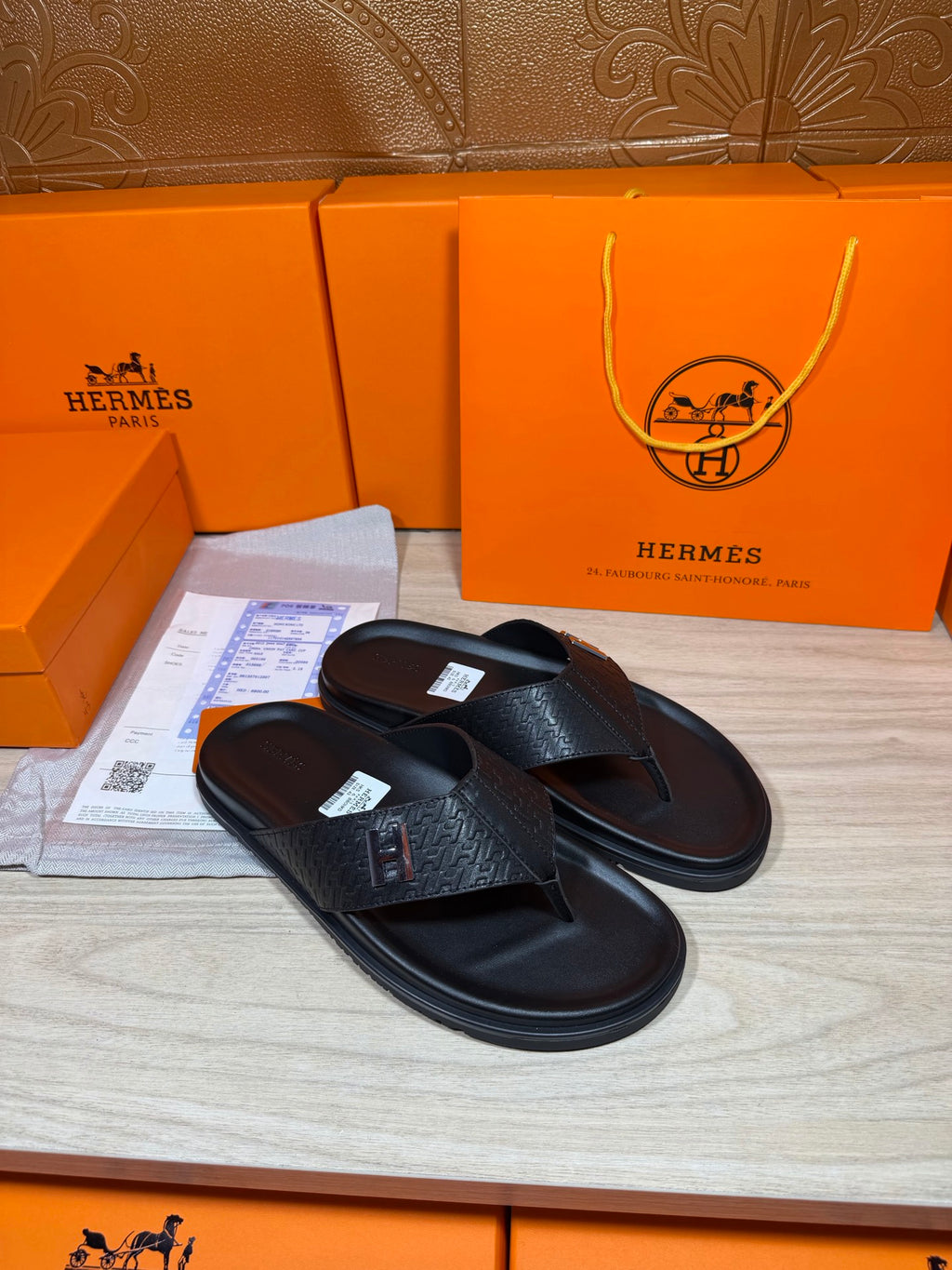Black leather slide sandals with embossed-look H logo strap on a flat sole