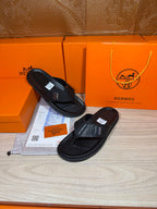 Black leather slide sandals with H logo strap, textured upper, and flat sole