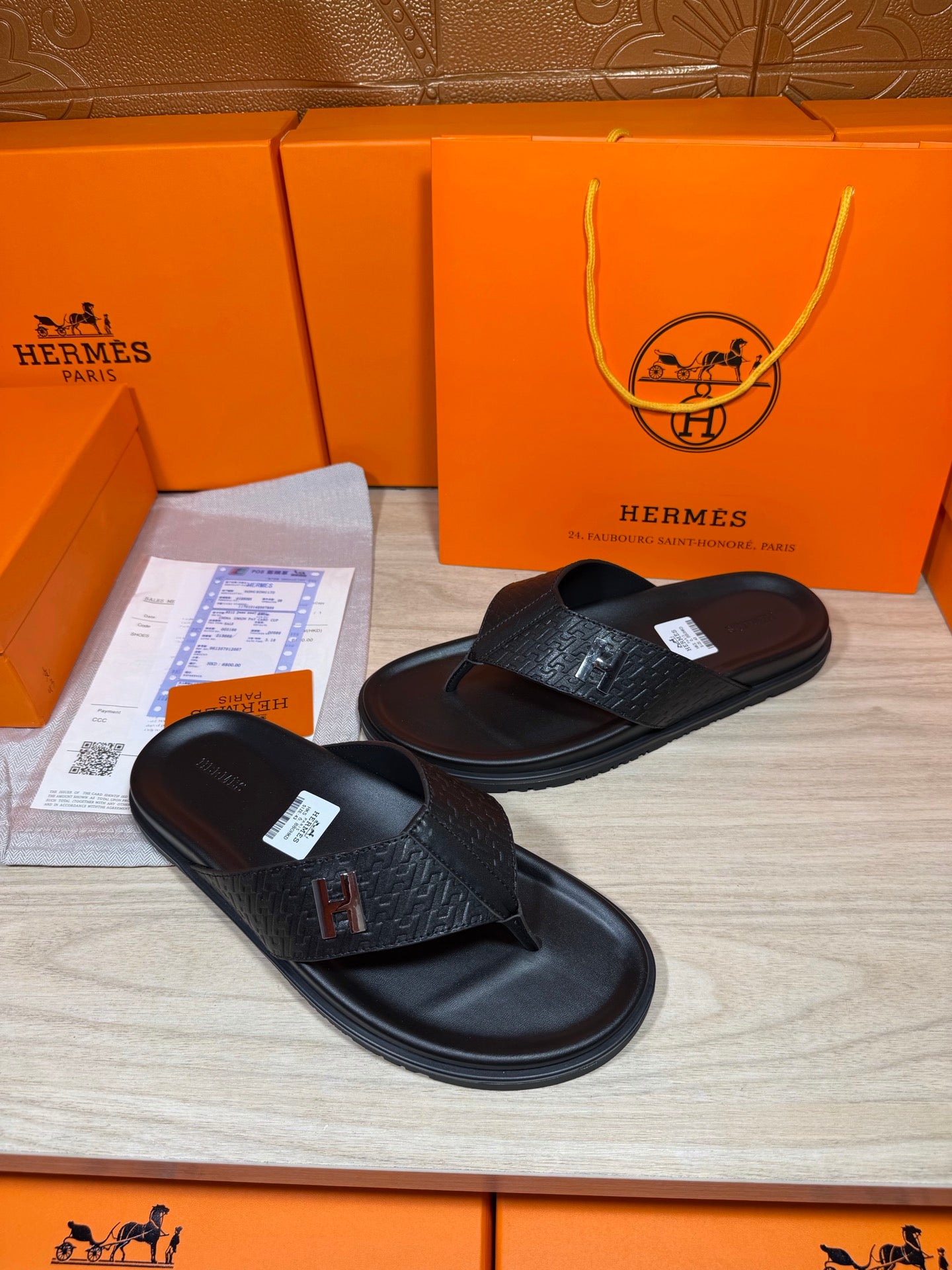 Black leather slide sandals showing H logo strap and textured upper