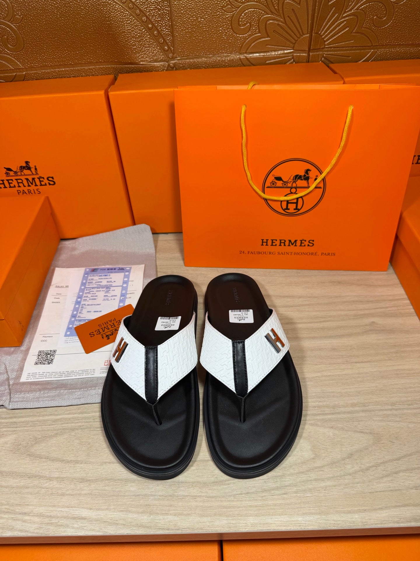Hermes leather sandals with black thong straps, white inlay, and H logo flat sole.