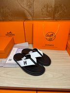 Hermes leather thong sandals with black straps, white inlay, and centered H logo.