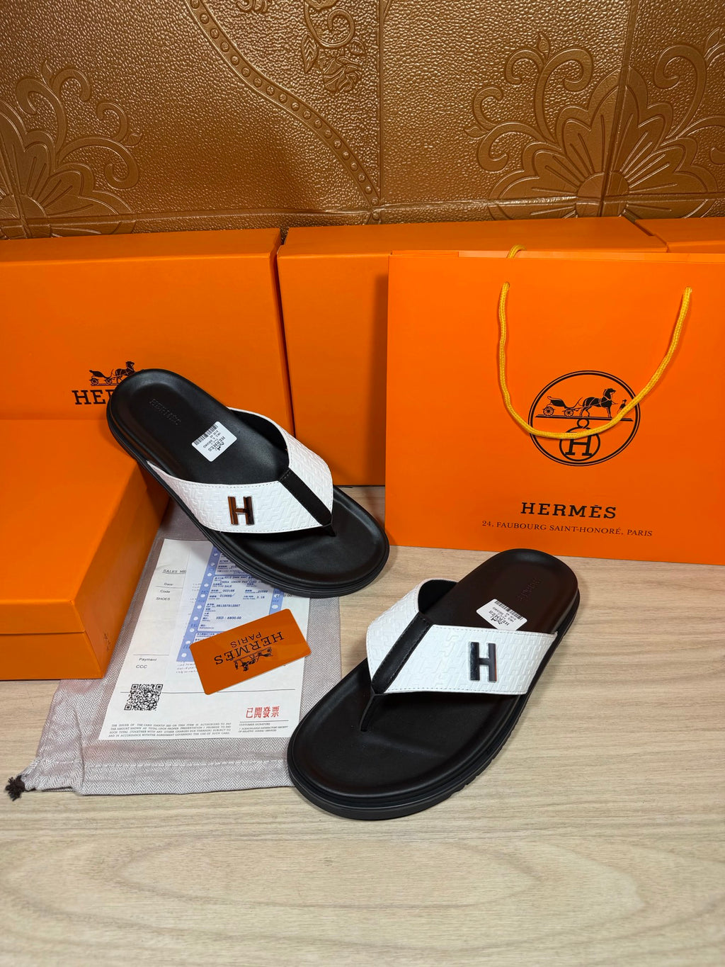 Hermes leather thong sandals in black with white strap panel and H logo detail.