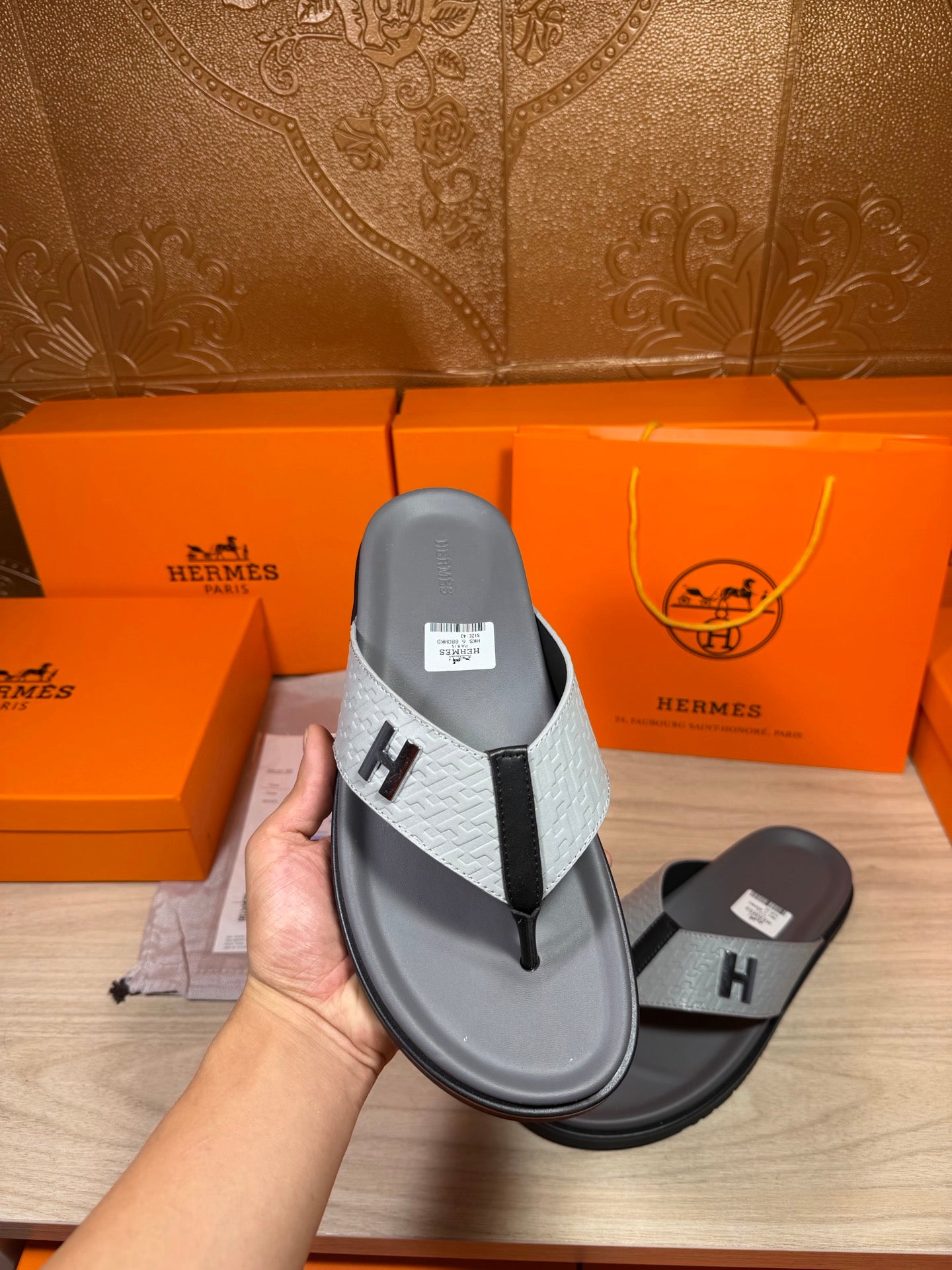 Hermes thong sandal held up, dark gray sole with gray H logo strap