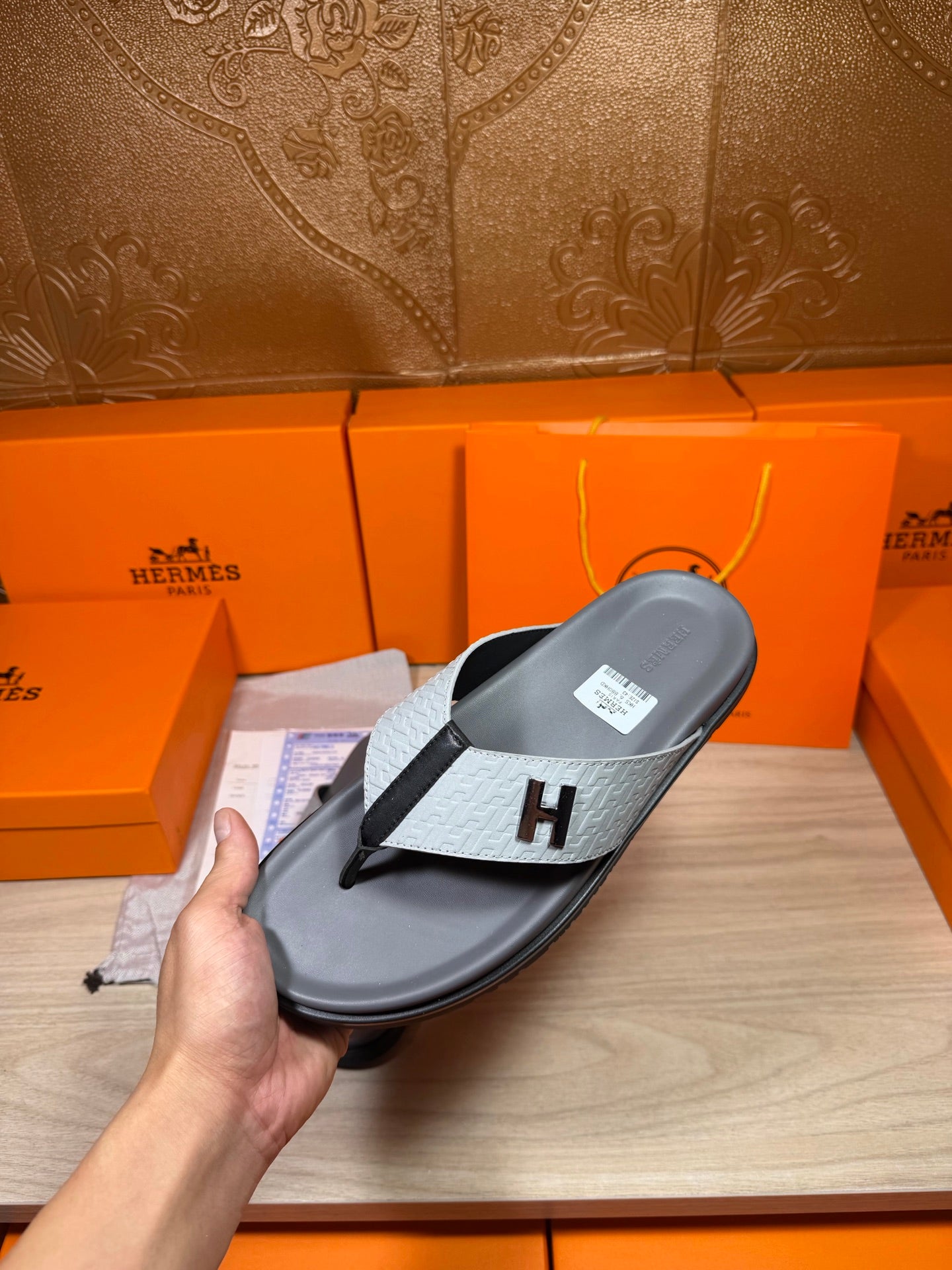 Hermes thong sandal on display, dark gray sole with gray H logo strap