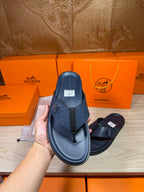 Hermes leather sandals in dark blue held for display, front strap with H emblem