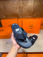 Hermes leather sandal in dark blue, close-up held in hand with H logo on strap