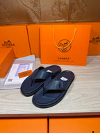 Hermes leather flip-flops in dark blue with textured straps, pair angled side view