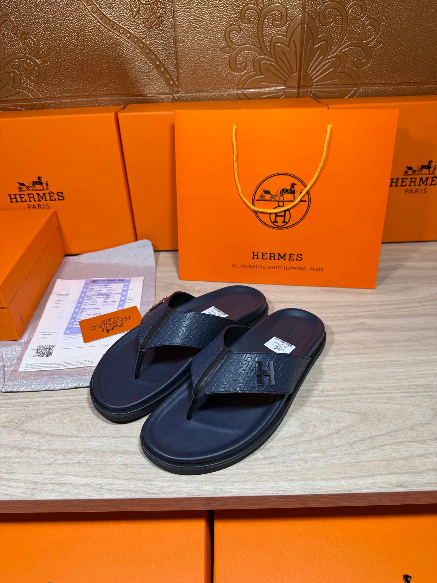 Hermes leather flip-flops in dark blue with textured straps, pair angled side view