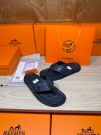 Hermes leather sandals in dark blue, laid flat side-by-side with H detail on straps