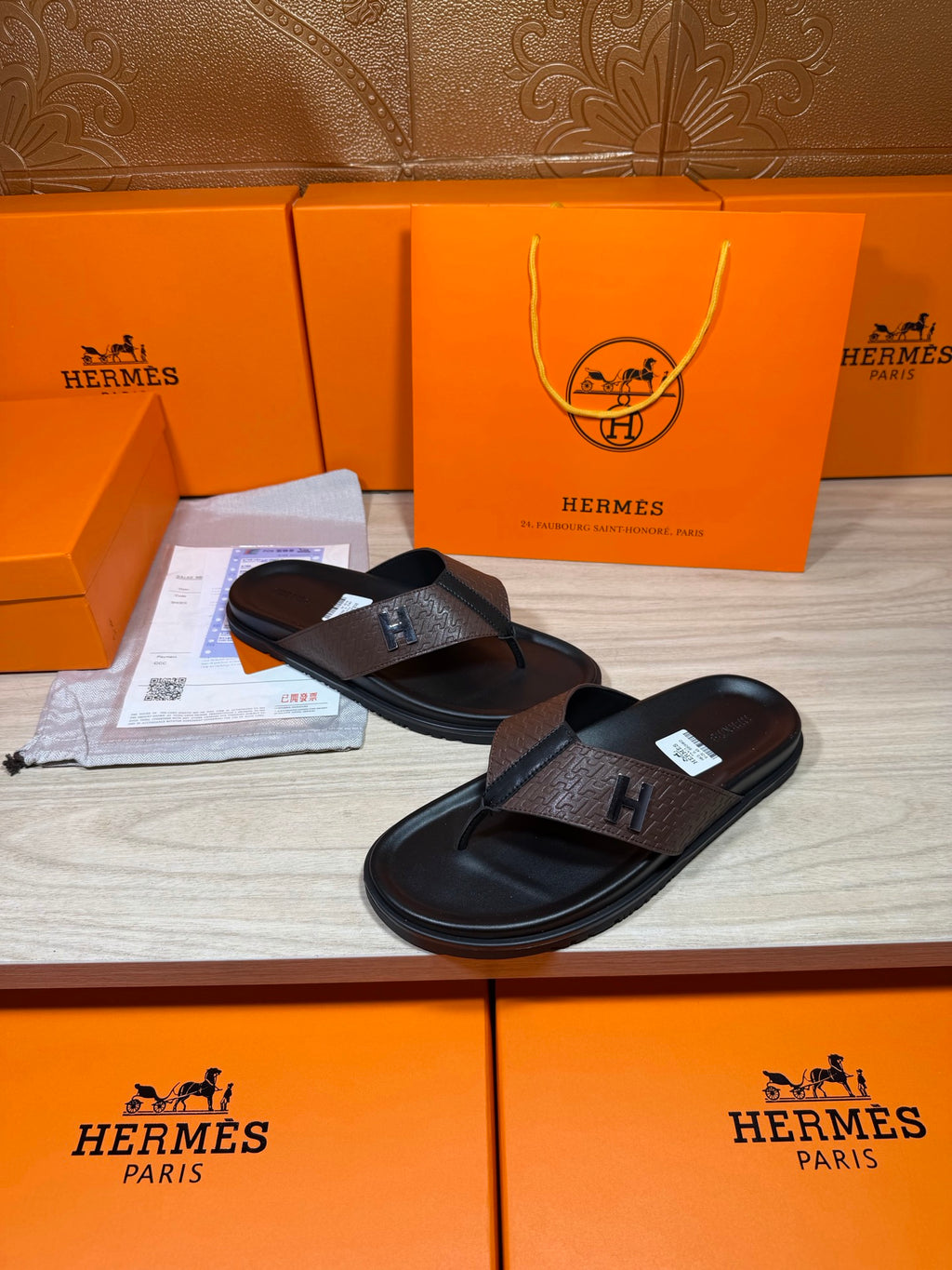 Brown and black H-logo thong sandals with black rubber footbed and toe strap