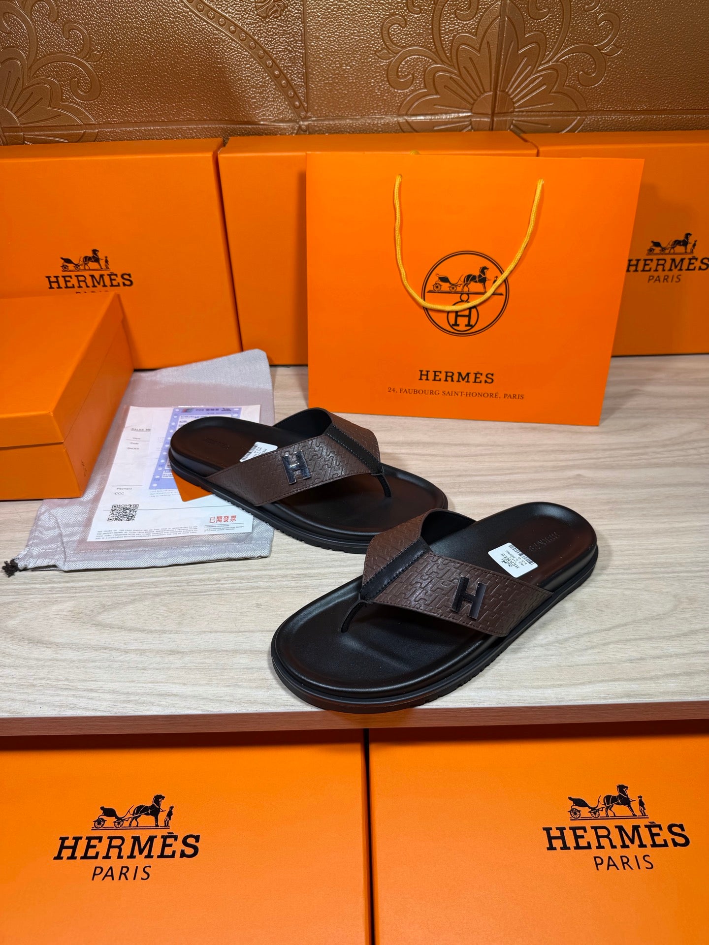 Brown and black H-logo thong sandals with black rubber footbed and toe strap