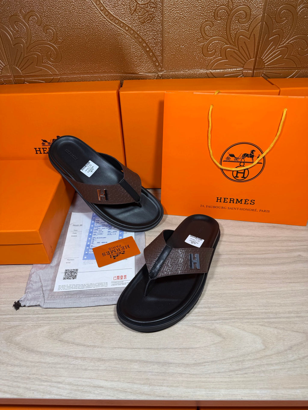Pair of black-and-brown H-logo thong sandals with textured brown toe strap