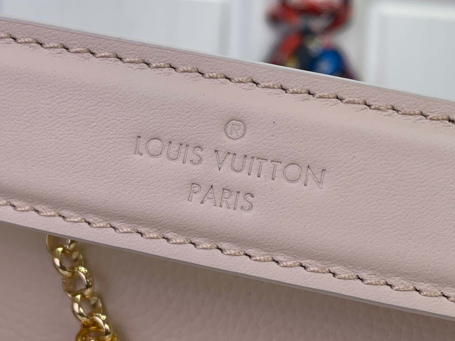 Louis Vuitton handbag strap close-up with debossed 'Louis Vuitton Paris' text