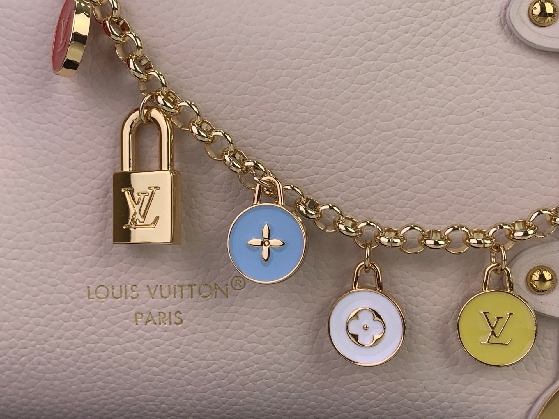 Louis Vuitton bag with pale pink leather, gold chain, padlock and round charms