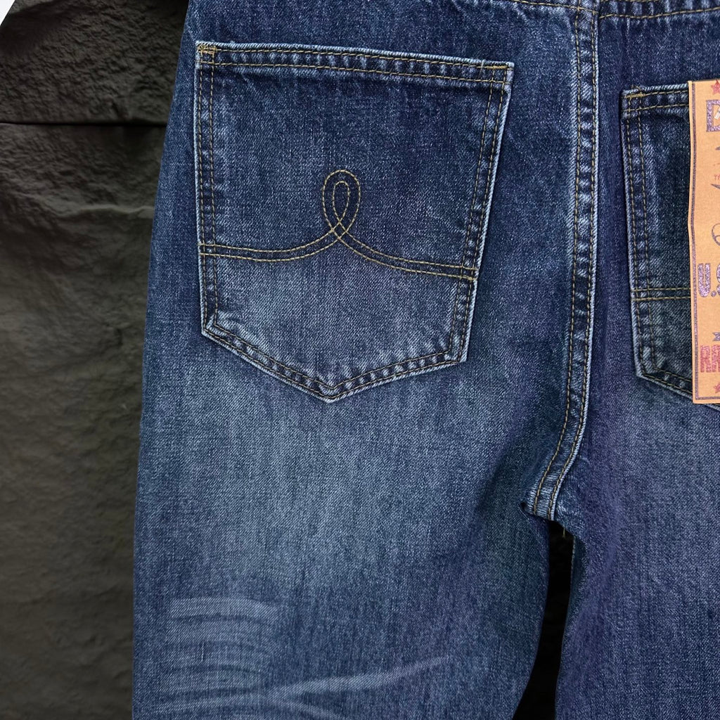 Blue denim jeans close-up of back pocket with curved stitch detail