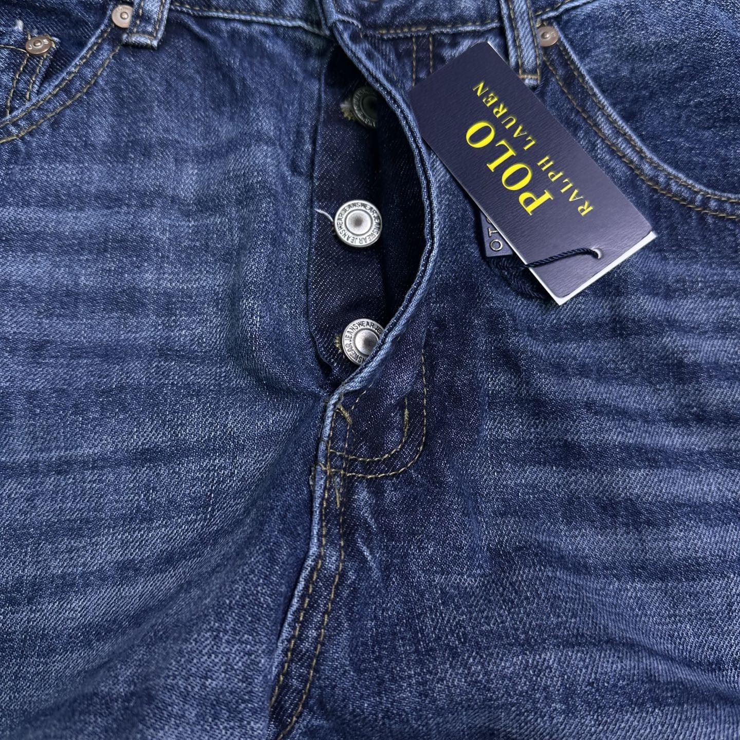 Blue denim jeans close-up of button fly and coin pocket.