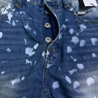 Blue denim jeans close-up of button fly and speckle print, curved pocket seam.