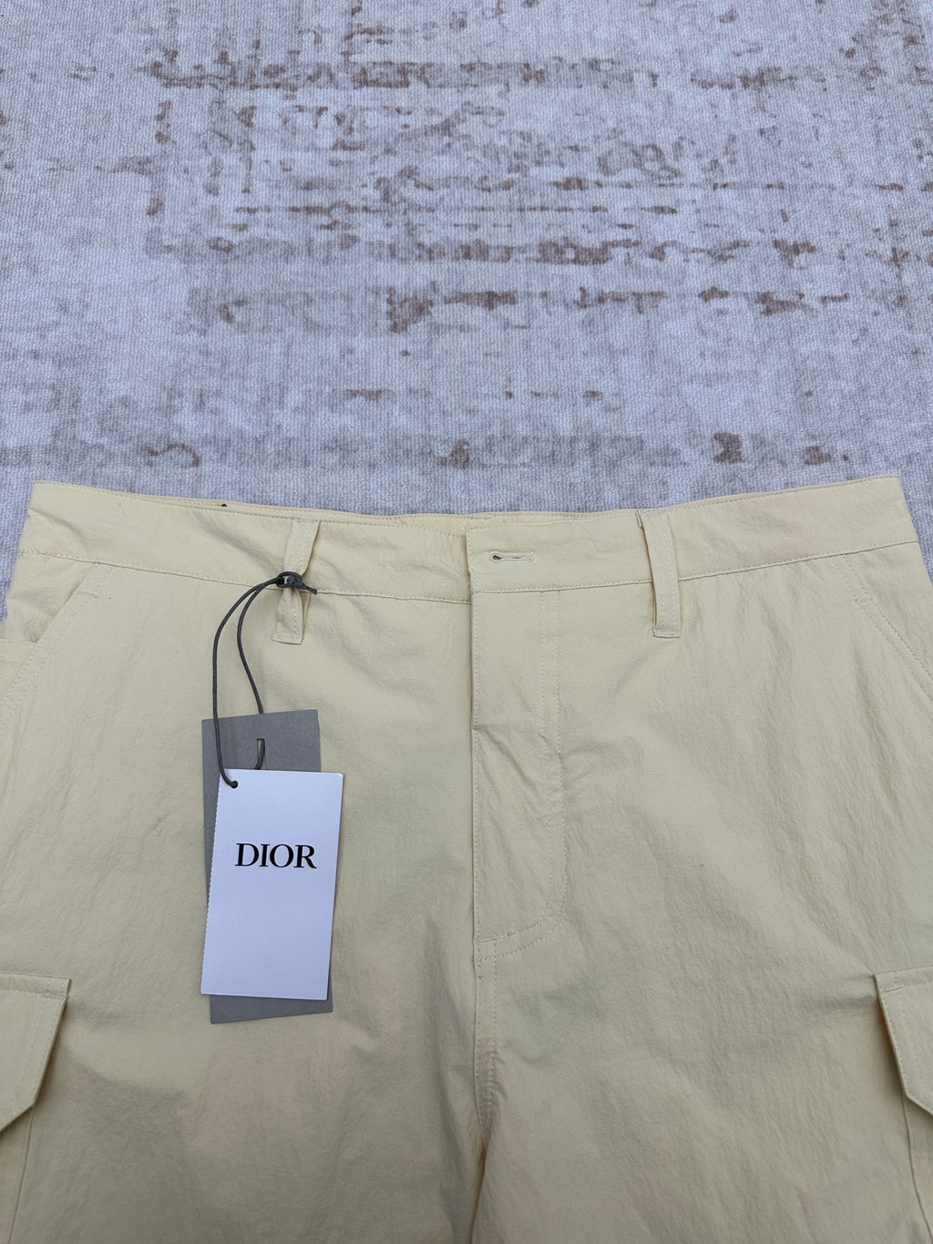 Light yellow shorts with drawstring waist and Dior hang tag