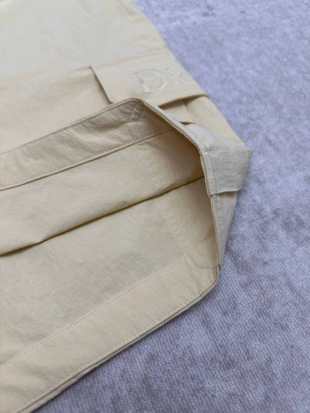 Light yellow shorts with curved seam and D embroidery patch at pocket