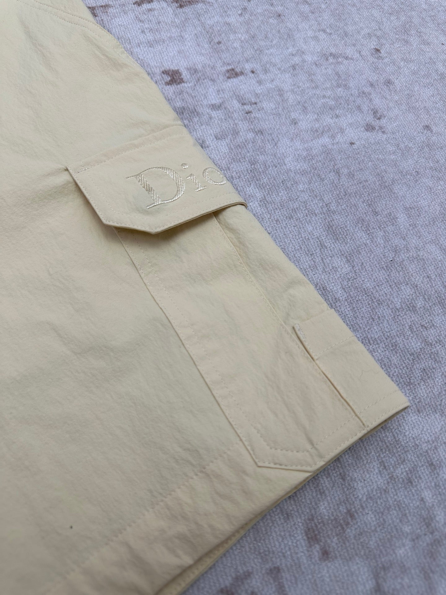 Light yellow shorts with stitched cargo pocket and D embroidery on hem