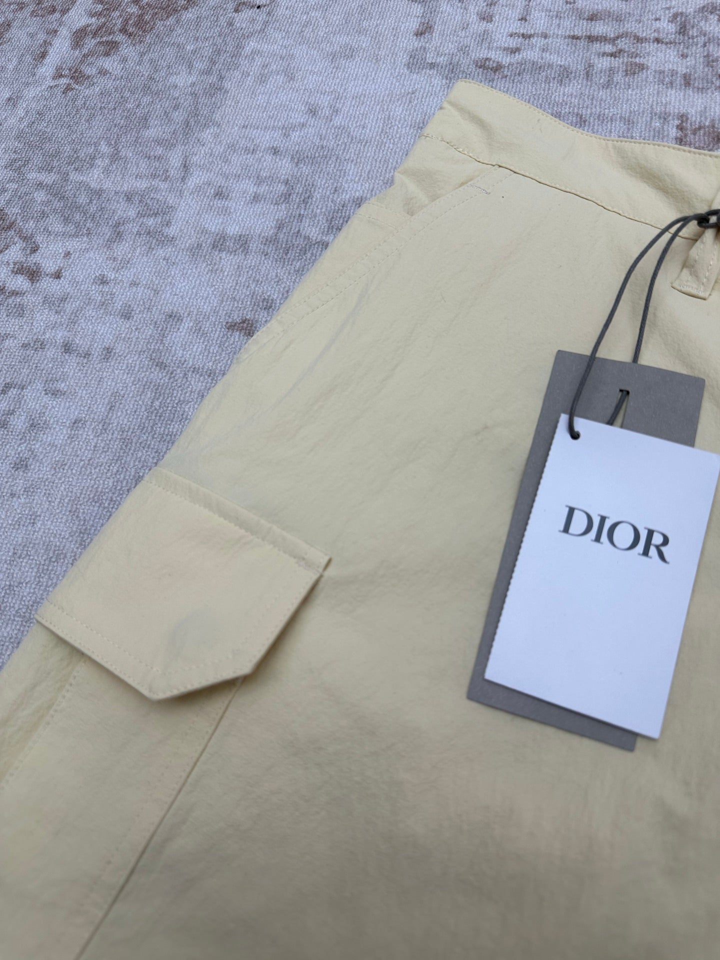 Light yellow shorts with cargo pocket and hanging Dior retail tag