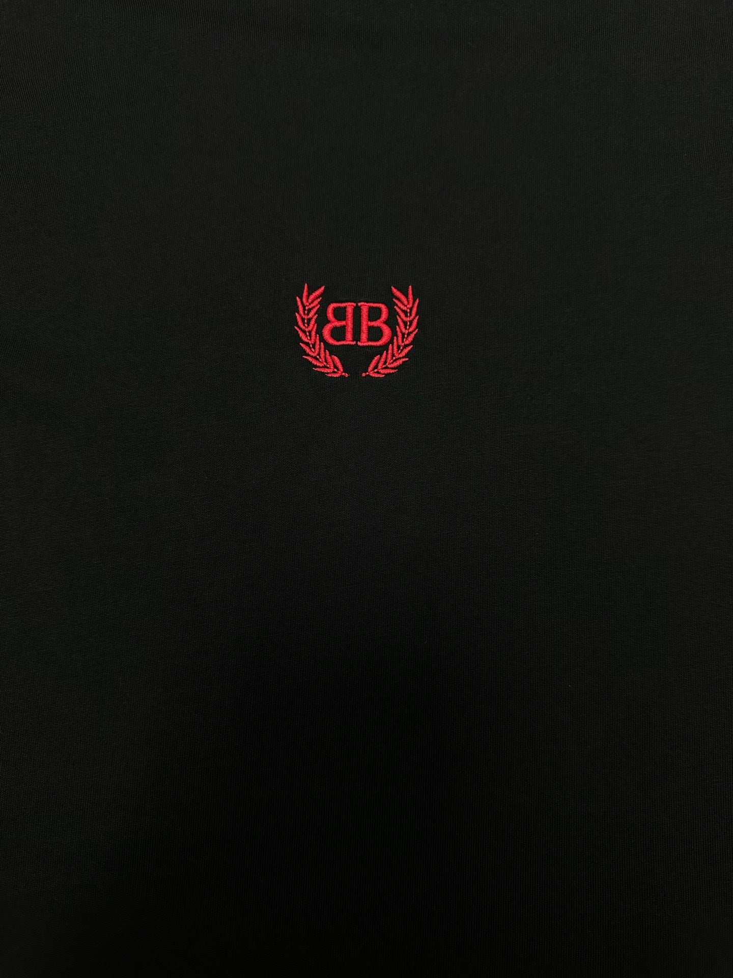 Black short-sleeve T-shirt with centered red crest logo