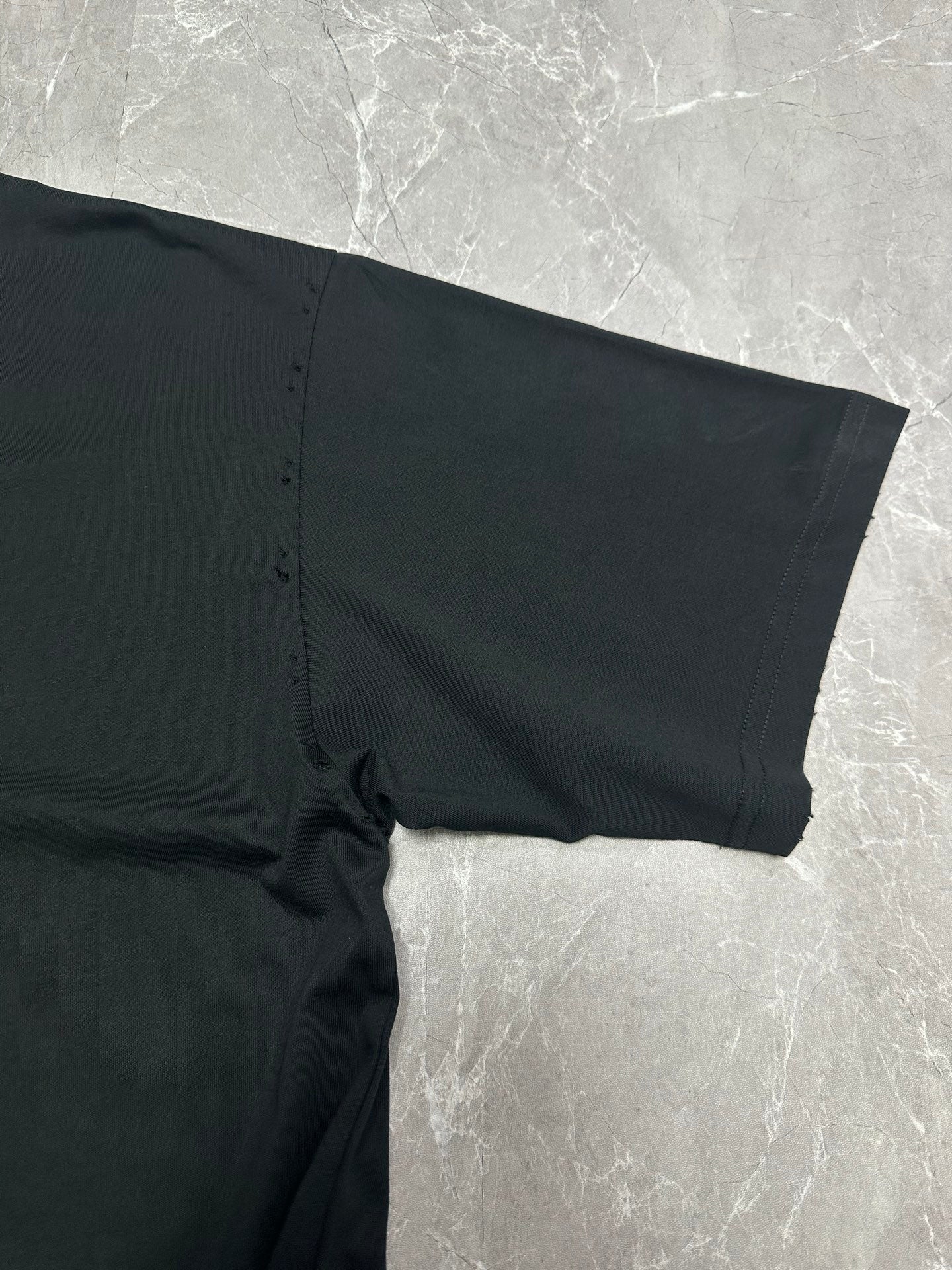 Black short-sleeve T-shirt sleeve and side seam close-up