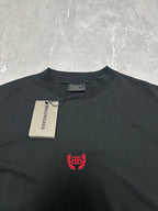 Black short-sleeve T-shirt with red crest logo and brand tag at collar