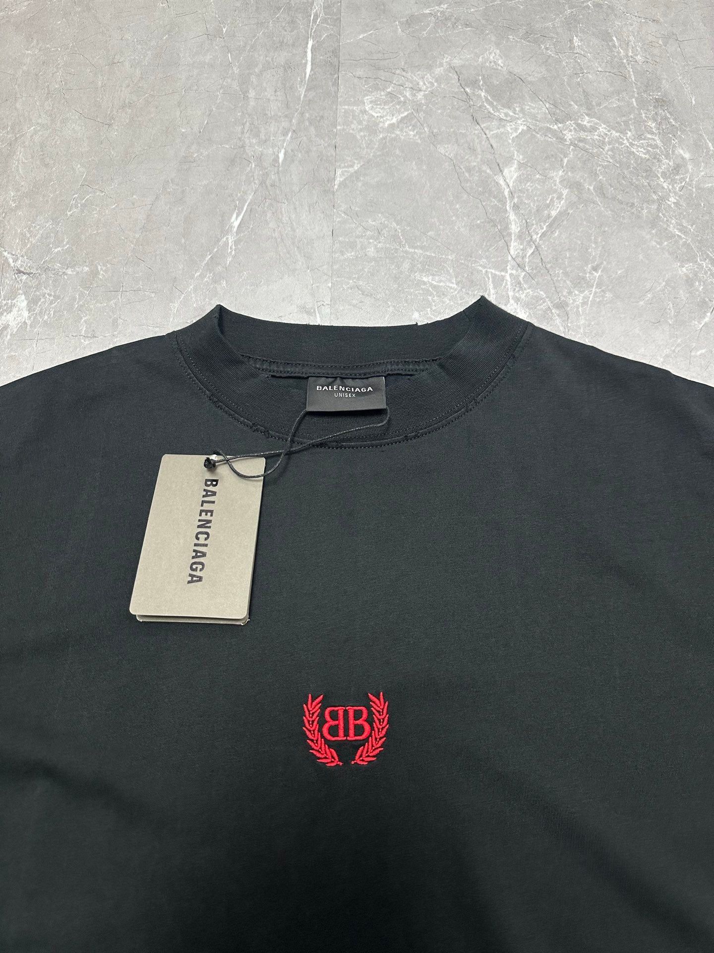Black short-sleeve T-shirt with red crest logo and brand tag at collar