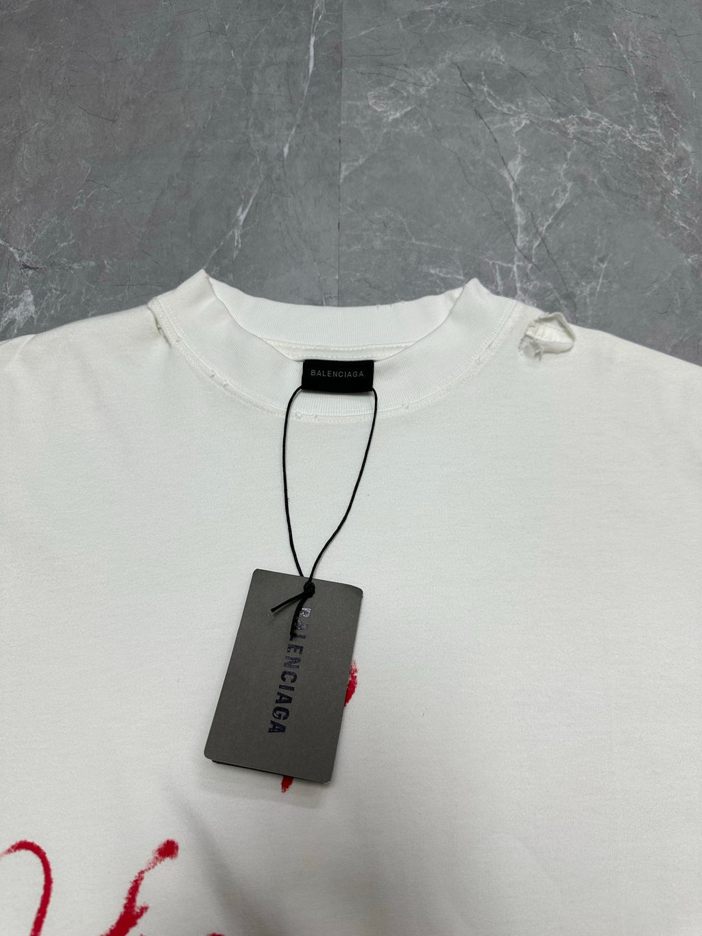 White crewneck T-shirt with black Balenciaga tag hanging at collar