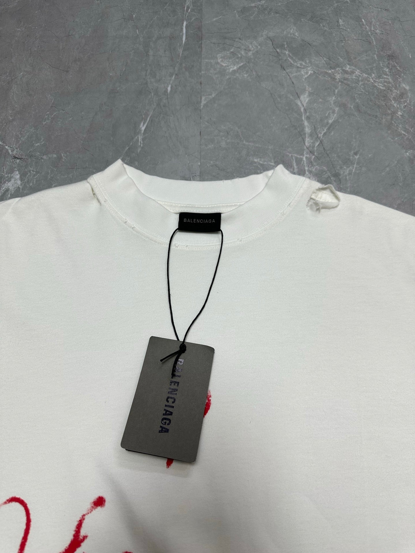 White crewneck T-shirt with black Balenciaga tag hanging at collar