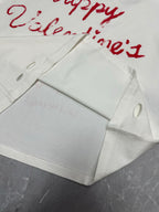 White T-shirt folded detail with red Valentine’s text and hanging tag