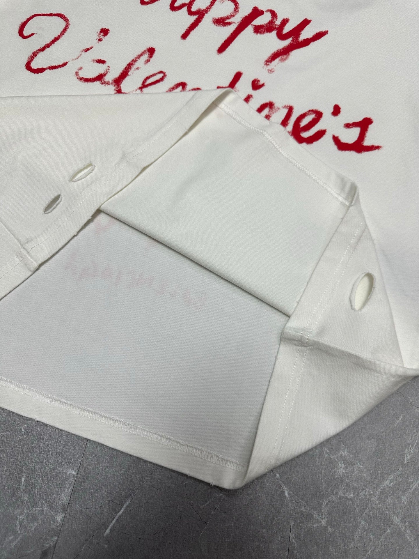 White T-shirt folded detail with red Valentine’s text and hanging tag