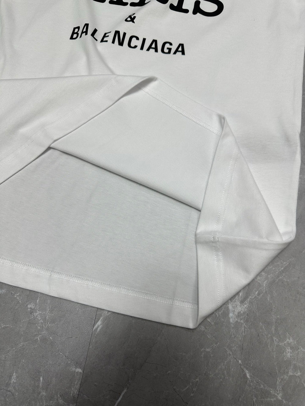 Balenciaga white short-sleeve T-shirt laid flat with graphic and curved hem
