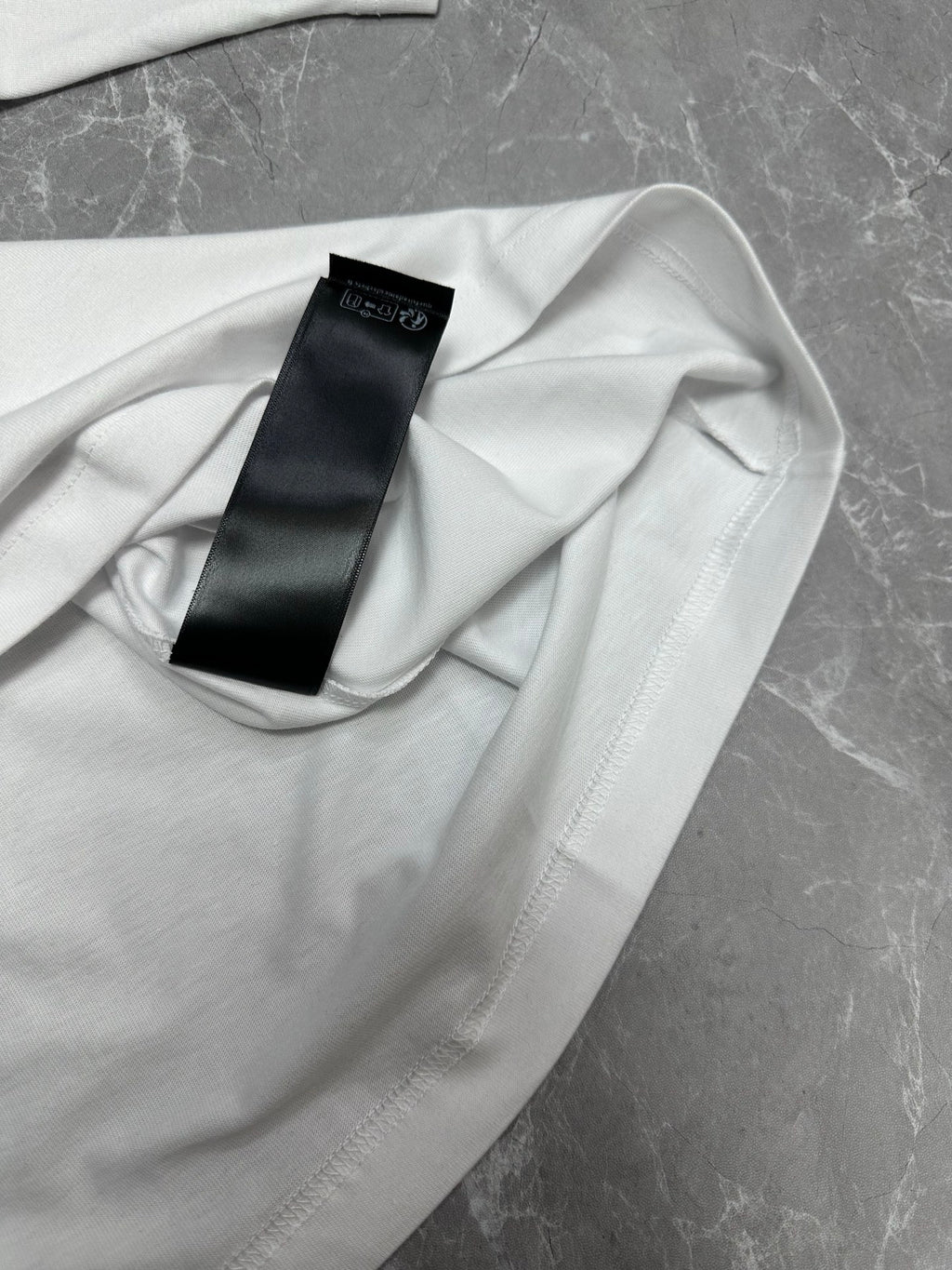 Balenciaga white short-sleeve T-shirt, care label tag close-up on fabric