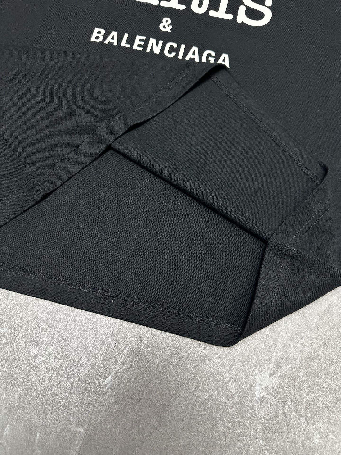 Black short-sleeve T-shirt with visible seams and BALENCIAGA logo text.