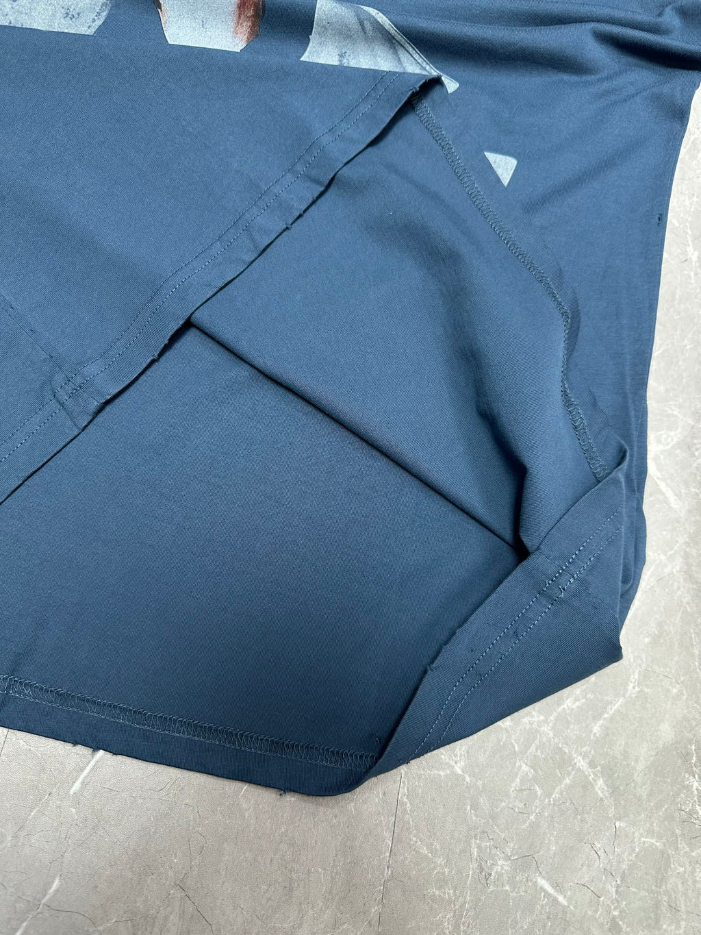 Blue T-shirt fabric and neckline seam detail, folded on a flat surface