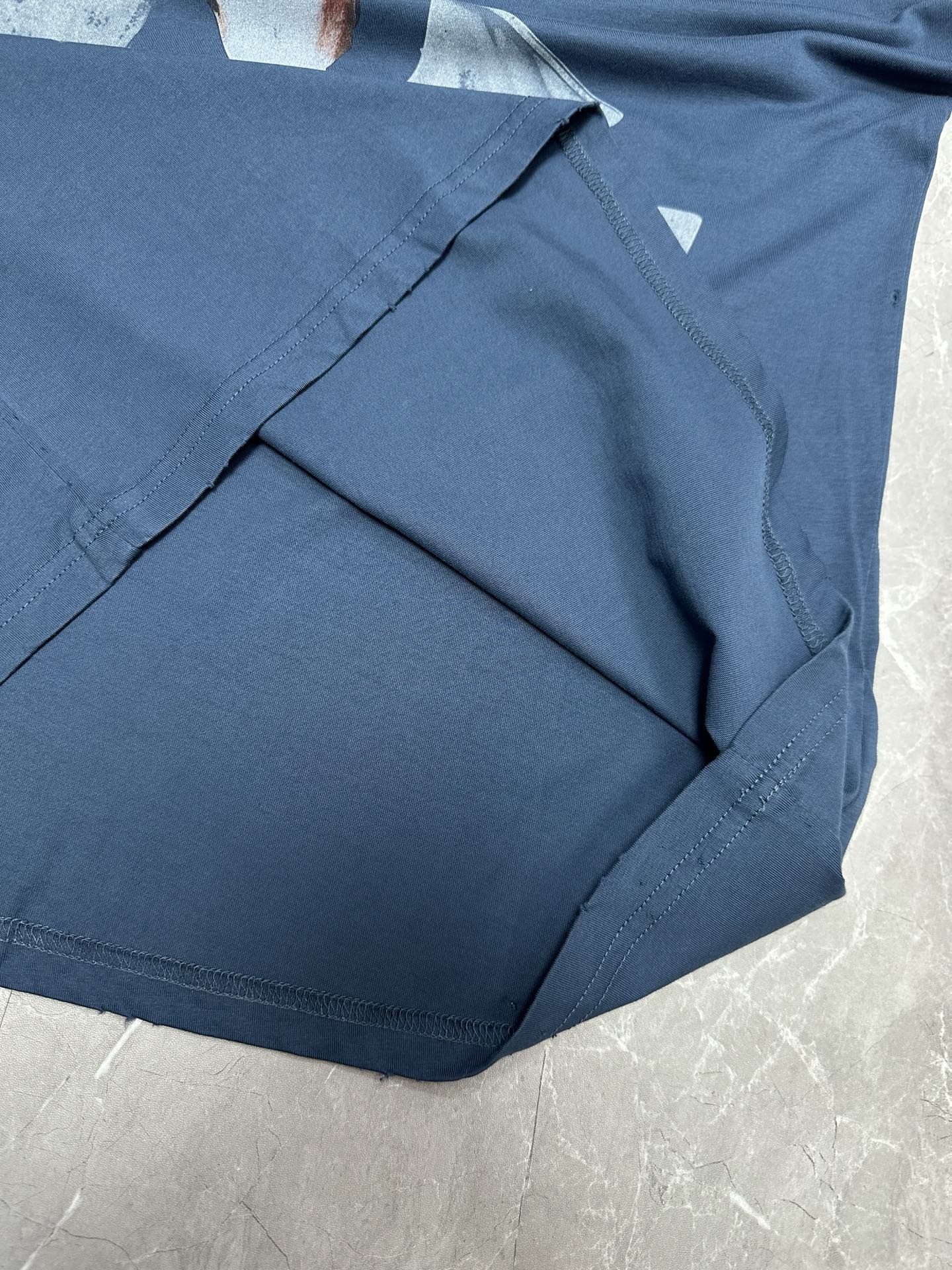 Blue T-shirt fabric and neckline seam detail, folded on a flat surface