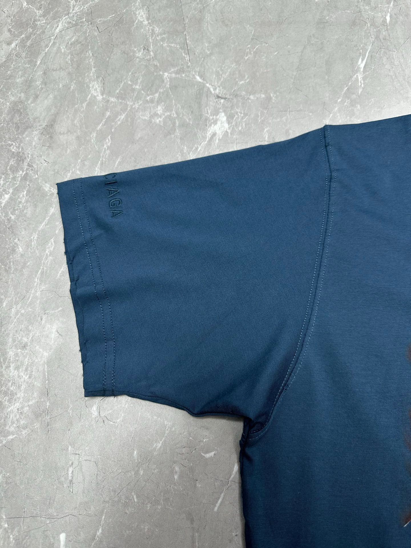 Blue T-shirt sleeve and side seam detail, laid flat