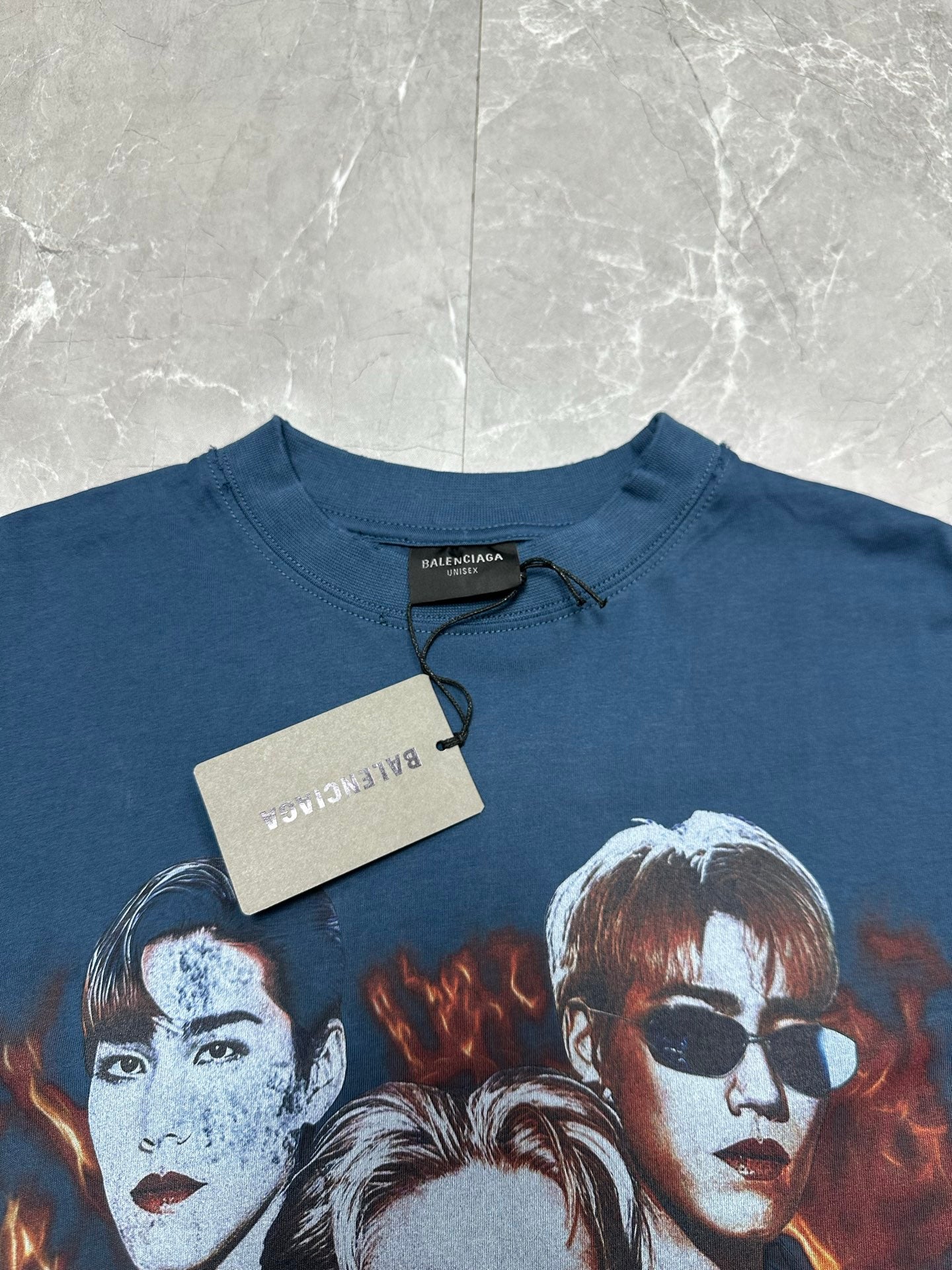 Blue graphic T-shirt close-up with Balenciaga brand tag at the collar
