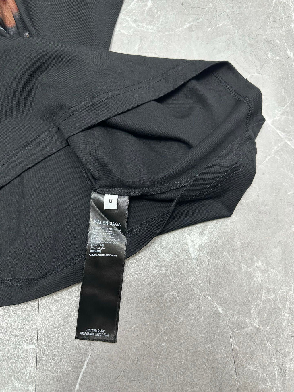 Black short-sleeve T-shirt with care tag and folded sleeve close-up