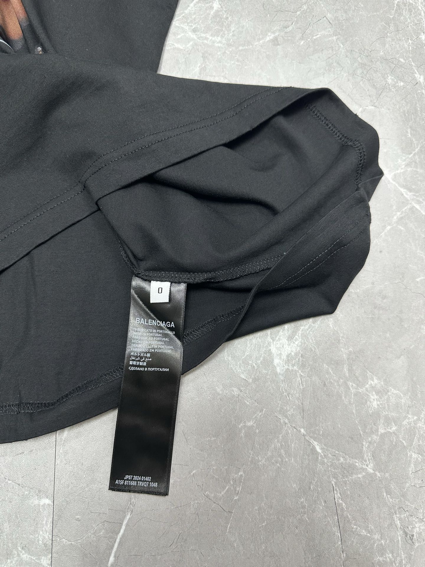 Black short-sleeve T-shirt with care tag and folded sleeve close-up