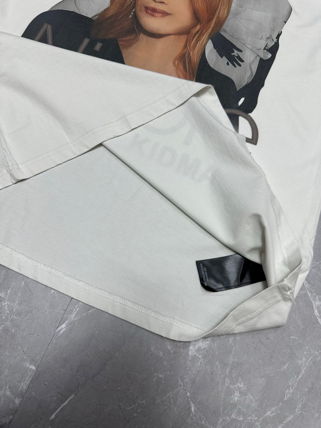 White graphic T-shirt with black side label near the hem and folded front