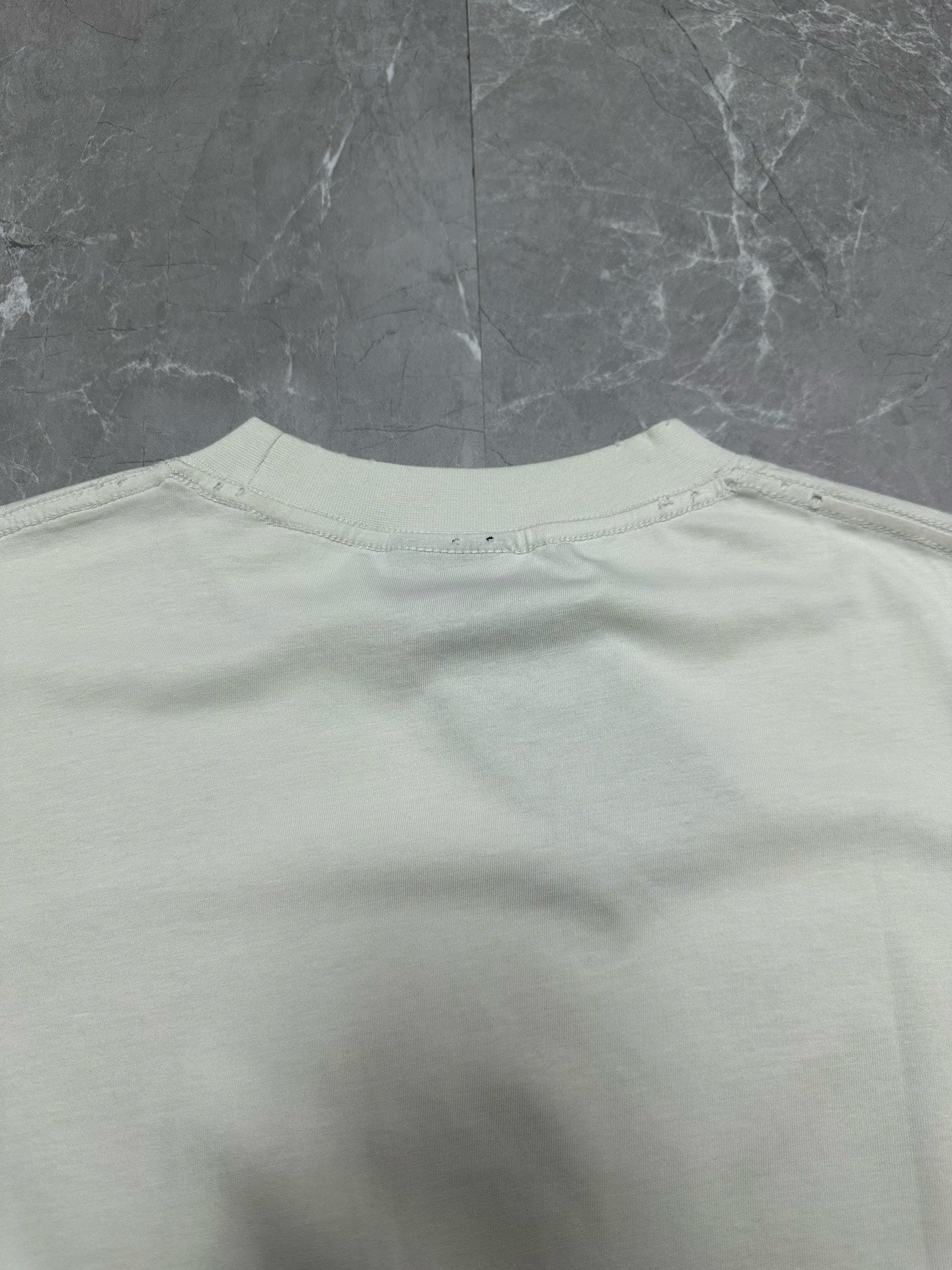 White crewneck T-shirt back with small brand tag at the neckline area