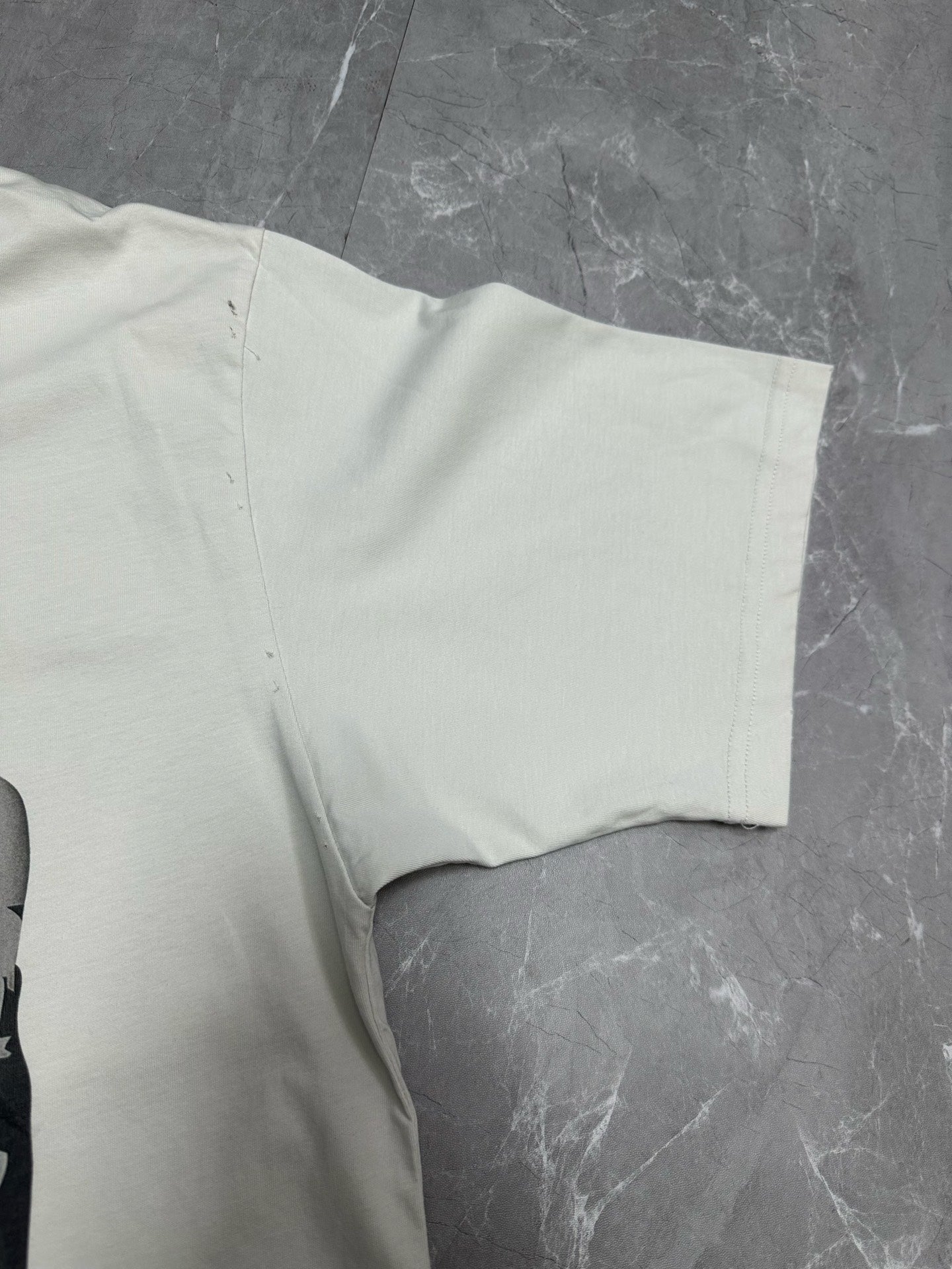 White T-shirt laid flat showing short sleeve and side seam near the hem