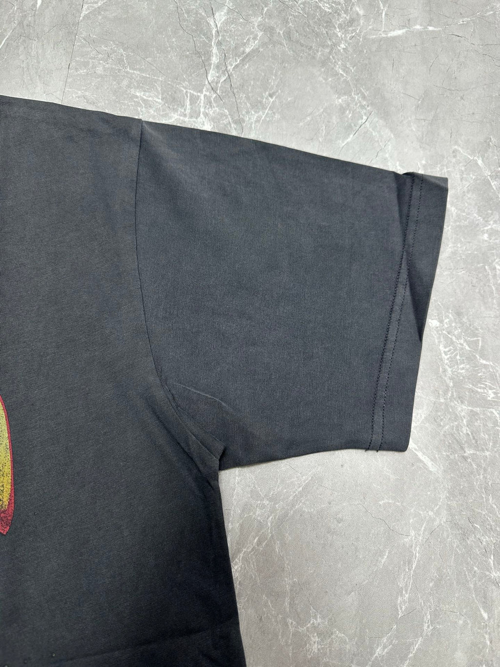 Dark charcoal graphic T-shirt short sleeve and draped fabric detail near hem