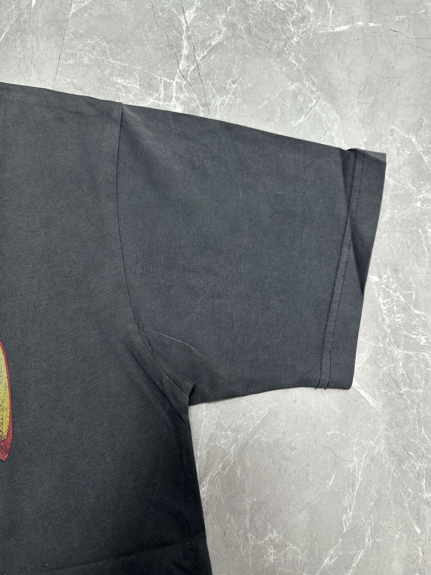 Dark charcoal graphic T-shirt short sleeve and draped fabric detail near hem